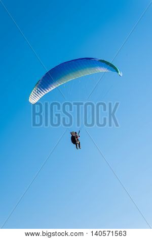 Paragliding in the sky. Man flying a paraglider on the sun.