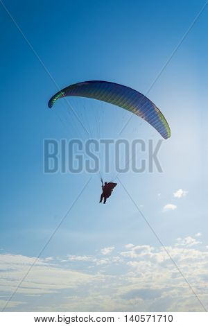 Paragliding in the sky. Man flying a paraglider on the sun.