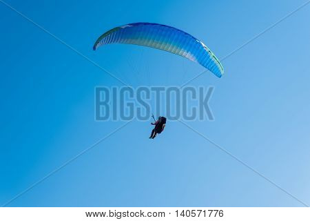 Paragliding in the sky. Man flying a paraglider on the sun.