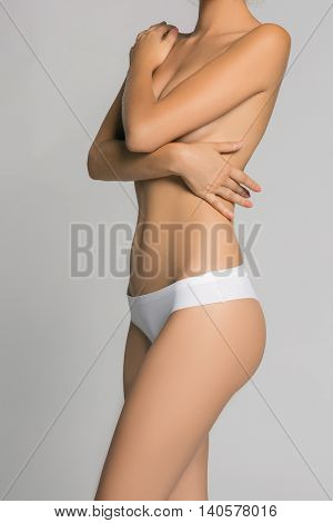 Beautiful young woman with clean skin nude topless breasts. Beauty lady covering her nude breast.