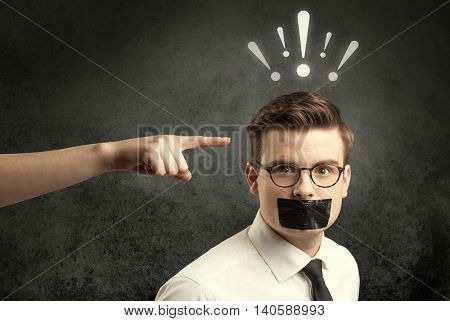 Caucasian hand pointing at employee in business suit, with drawn exclamation marks above his head