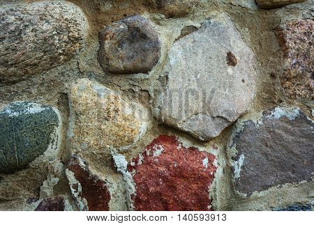 Wall built of large fieldstone combined cement. Close horizontal view.
