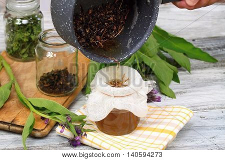Alternative medicine filtering comfrey ointment good for bones decorated with fresh comfrey and dried comfrey roots
