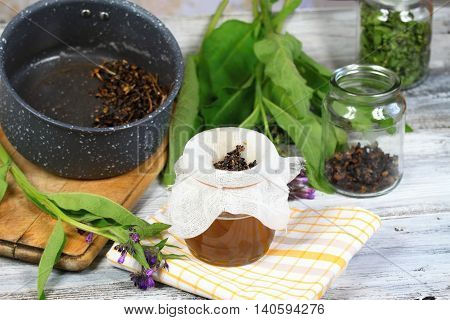 Alternative medicine filtering comfrey ointment good for bones decorated with fresh comfrey and dried comfrey roots