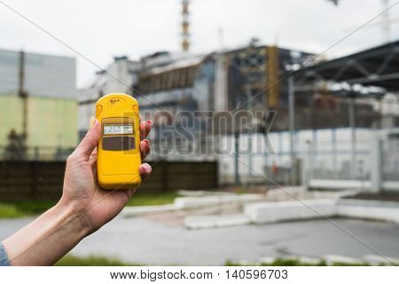 radiometer in hand with fourth Chernobyl reactor on the background