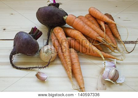 Harvest fresh vegetables: carrots beets garlic onion on a wooden background.