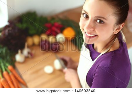 Young woman cutting vegetables in the kitchen .