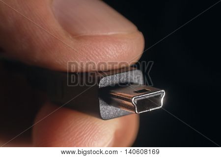 Hand holding black mini USB cable. Man's hand holds a USB mini Connector.
Closeup man hand holding mini USB cable.Selective focus and shallow Depth of field.