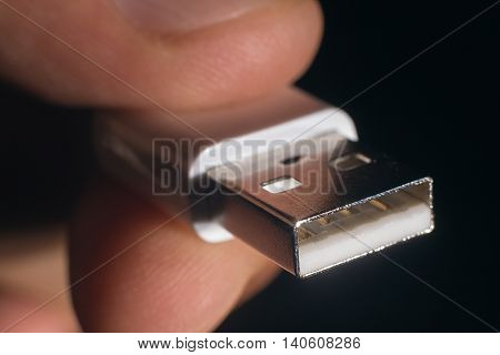 Hand holding white USB cable. Man's hand holds a USB Connector.
Closeup man hand holding USB cable.Selective focus and shallow Depth of field.