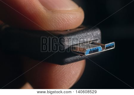 Hand holding black micro USB 3.0 cable. Man's hand holds a USB Connector.
Closeup man hand holding USB cable.Selective focus and shallow Depth of field.