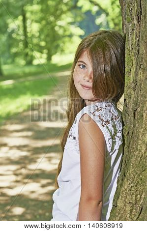View of a young girl standing near a tree trunk