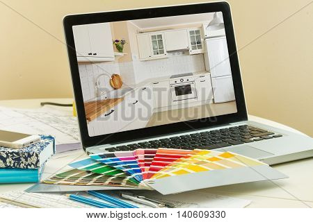 designer's working table - open notebook with refubrished kitchen and colour charts