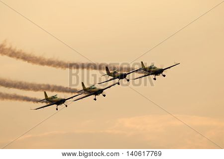 BUCHAREST (ROMANIA) - 30 JUNE 2016: Silhouette of airplanes (Aeroclub Roman Team) performing acrobatic flight at sundown. Trace of Smoke behind it