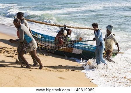 Pondichery, Tamil Nadu, India - February 27, 2014 : Traditional fishermen on beach, on sea, on sand. Long boats, Hard work poor people
