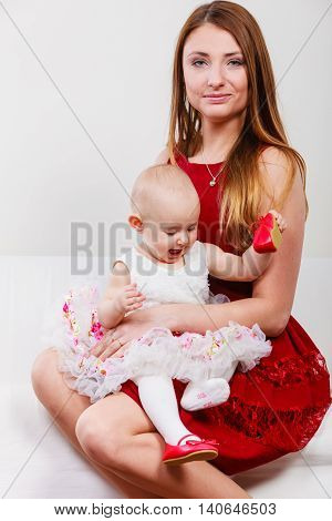 Single parent concept. Young elegant mother with baby girl in princess ballerina dress on mommy knees. Parenthood.