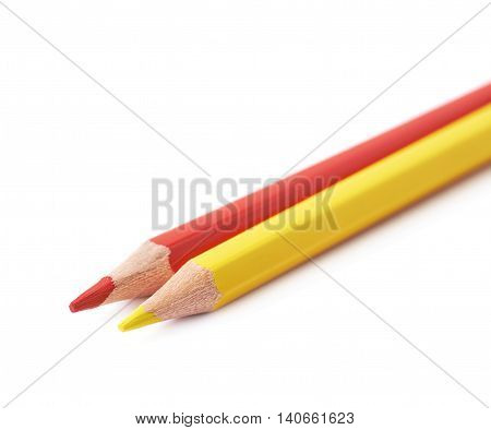 Two red and yellow colored drawing pencils composition isolated over the white background, close-up crop fragment