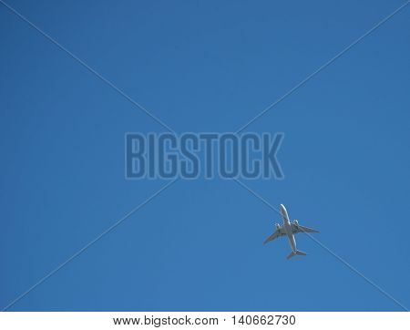 Passenger jet from below surrounded by clear blue sky