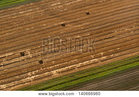 Top view of sloping wheat field with straw bales