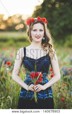 Beautiful young woman on the poppy field in sunlight