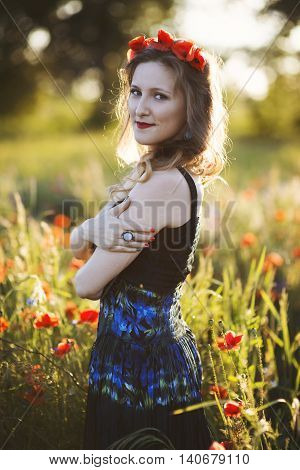 Beautiful young woman on the poppy field in sunlight