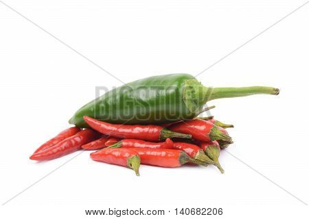 Pile of red italian peppers with a green jalapeno over it, composition isolated over the white background