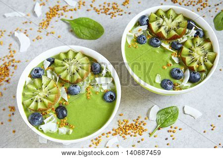 breakfast green smoothie bowl topped with kiwi, blueberry, coconutflake and bee pollen