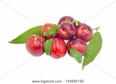 Several ripe fresh nectarines with leaves on a light background