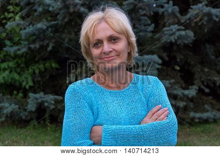 Smiling happy ellderly woman stands with crossed arms