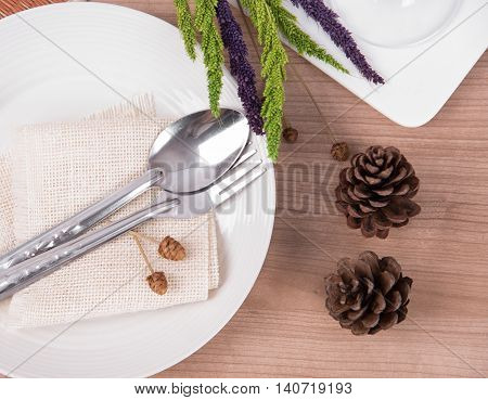 Dining table setting white plate with flower wineglass vintage crockery and spoon fork on wood table background.