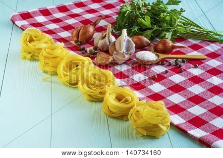 Italian food cooking ingredients. Pasta sun-dried tomatoes onions garlic spices salt in the wooden background.