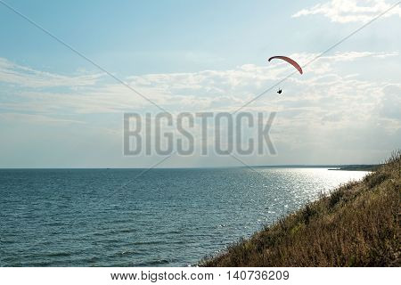 Paragliding in the sky. Man flying a paraglider on the sun.
