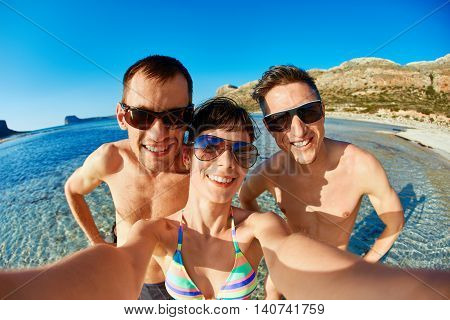 young happy couple friends on the beach taking selfie on sea background. Balos beach, Crete, Greece.