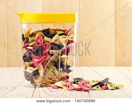raw bow-knot pasta of different color in plastic container