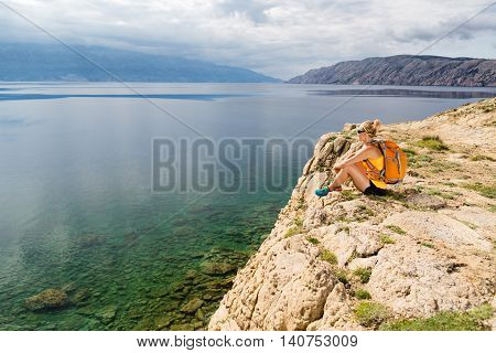 Woman hiker hiking with backpack looking at sea and mountains view. Recreation and healthy lifestyle outdoors in summer nature. Beautiful inspirational landscape. Trekking and activity concept.