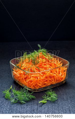 Carrot salad in a glass bowl against a dark background