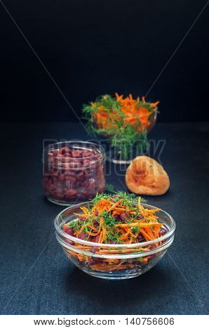 Carrot salad with beans against a dark background