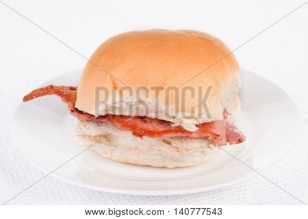Bacon roll bap or bun on a white plate. Selective focus