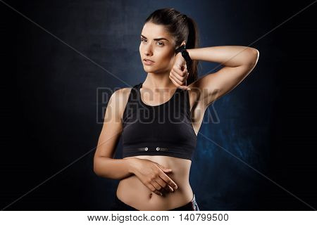 Portrait of young beautiful brunette  sportive girl posing over dark background. Copy space.