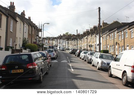LONDON, UNITED KINGDOM - SEMPTEMBER 12 2015: Row of traditional British houses in a street in the suburbs of London with car parked on the street