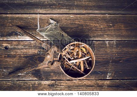 old rusty pinchers with can of nails on wooden boards background