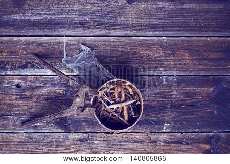 old rusty pinchers with can of nails on wooden boards background
