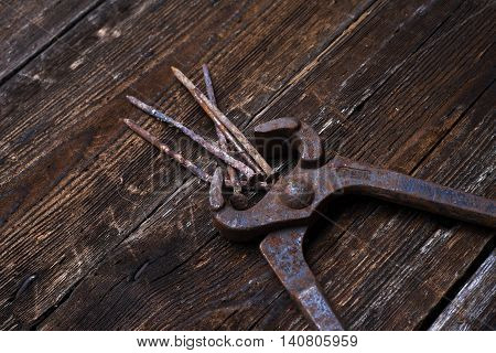 old rusty tongs with nails on wooden boards background