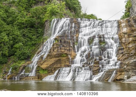 Ithaca Falls a waterfall in New York's Finger Lakes Region cascades down a tall rocky cliff.