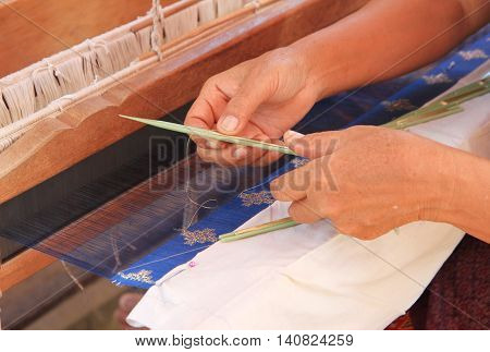 Close up of woman hand weaving traditional silk farbric on loom