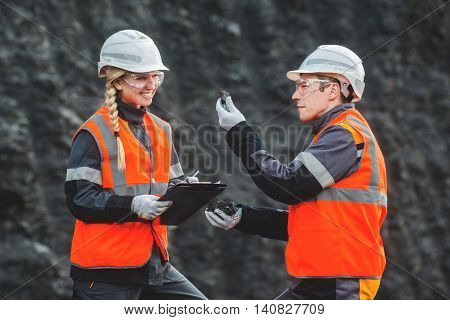 Two speacialists examining coal at an open pit