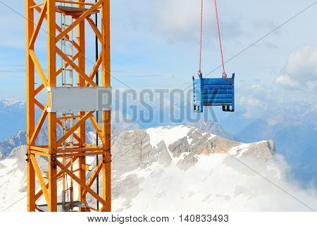 Crane with load on Germany's highest construction site in 2962m. Building the new Zugspitze cable car for tourists and skiers.