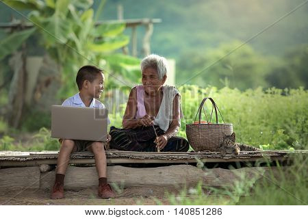 A boy and grandmother with a laptop at cottage