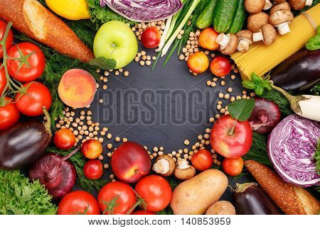 Frame of colorful different fruits vegetables pasta chickpea and bread on dark surface. Frame of colorful different food top view