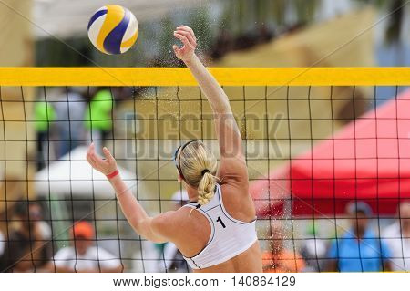 Volleyball player is a female athlete beach volleyball player rising up to make a play on the ball.