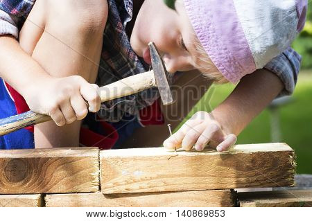 Boy learns to hammer nails in a garden